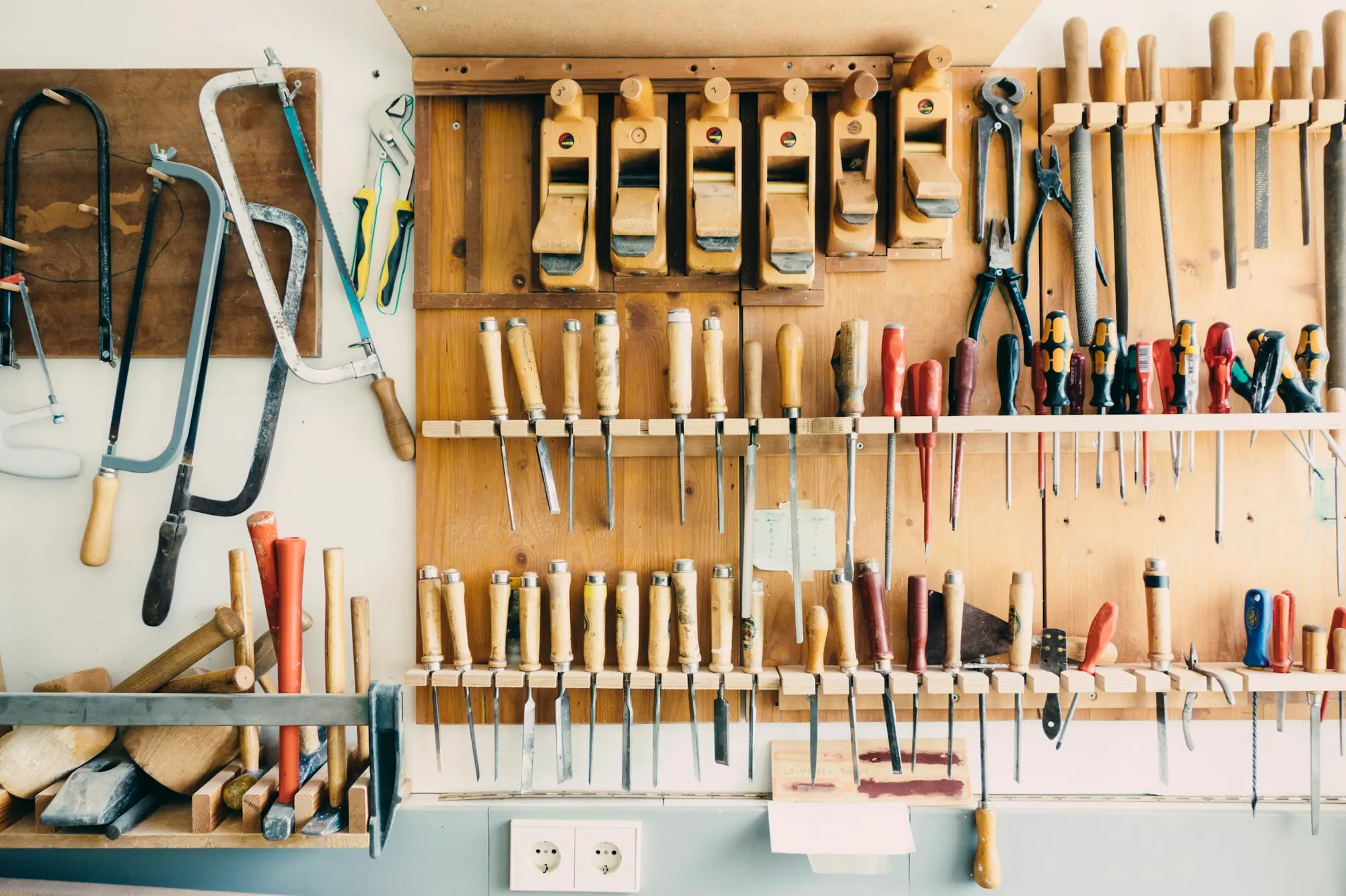 A workshop wall lined with saws, chisels and hand tools