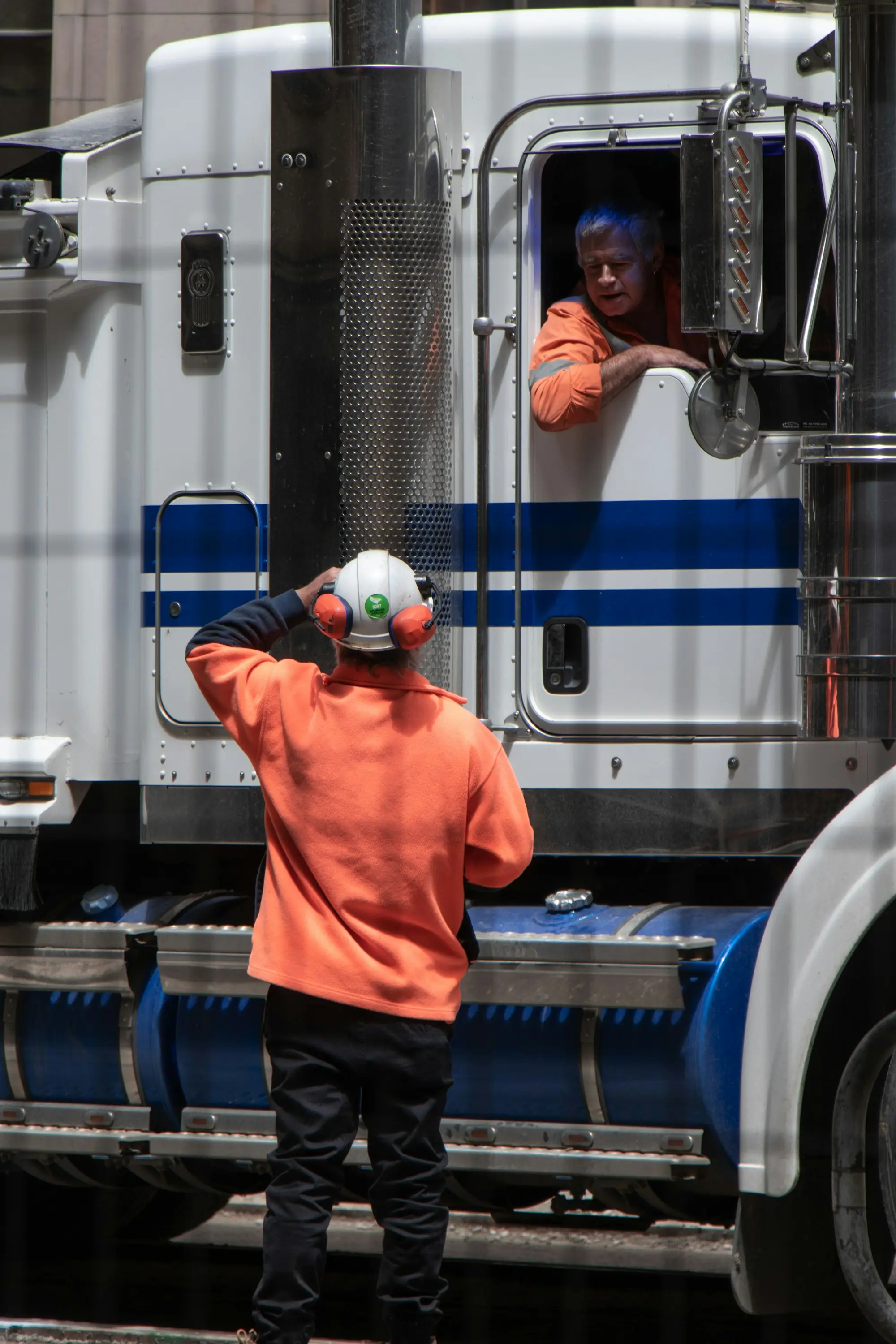 A worker in hi-vis guiding a freight truck driver in Melbourne
