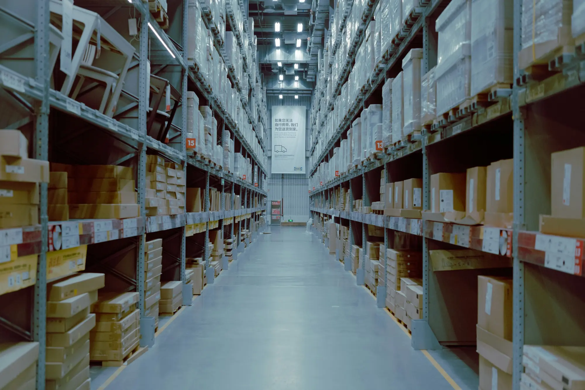 A warehouse aisle lined with shelves of boxed stock